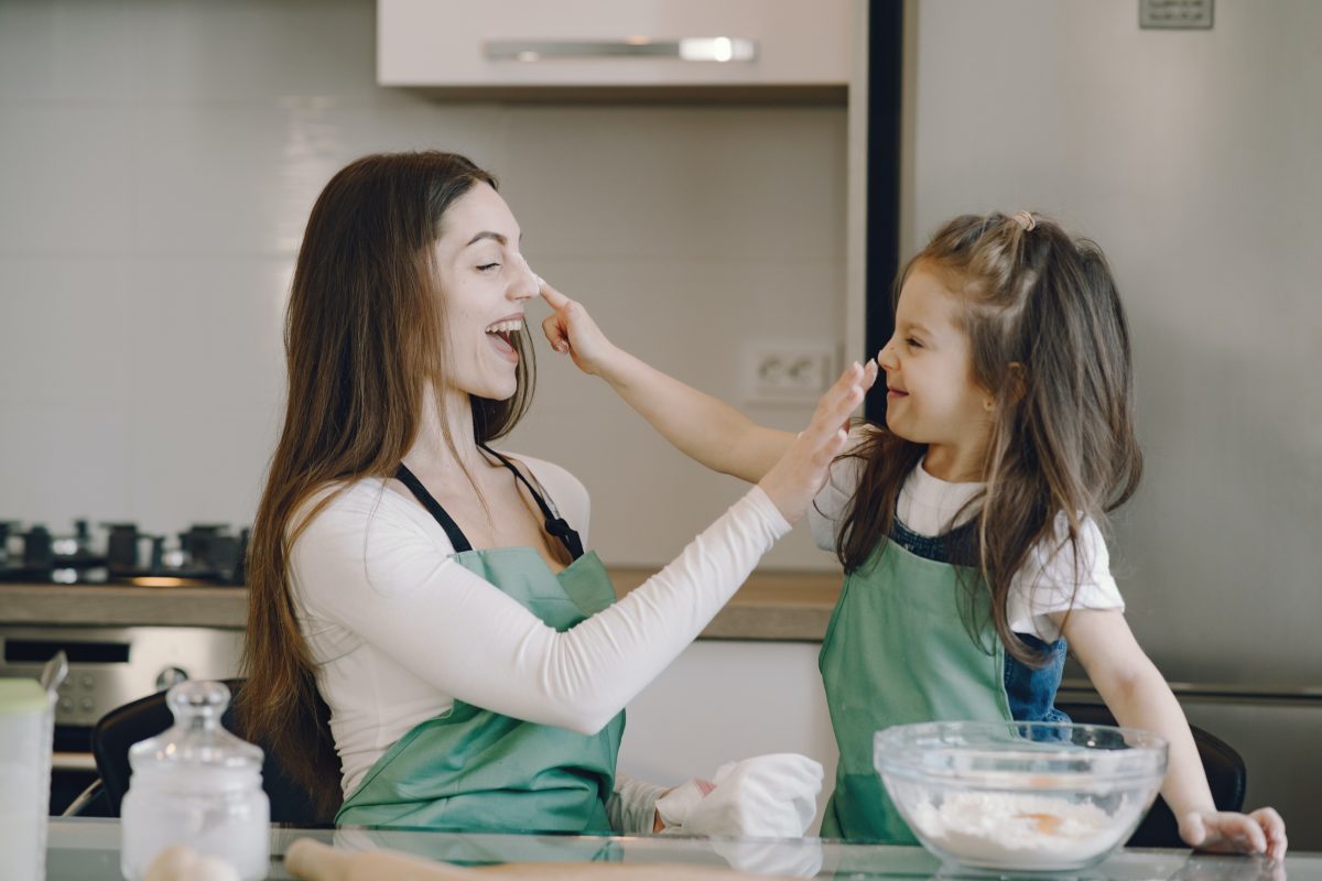 An nanny and a child playing happily while baking.