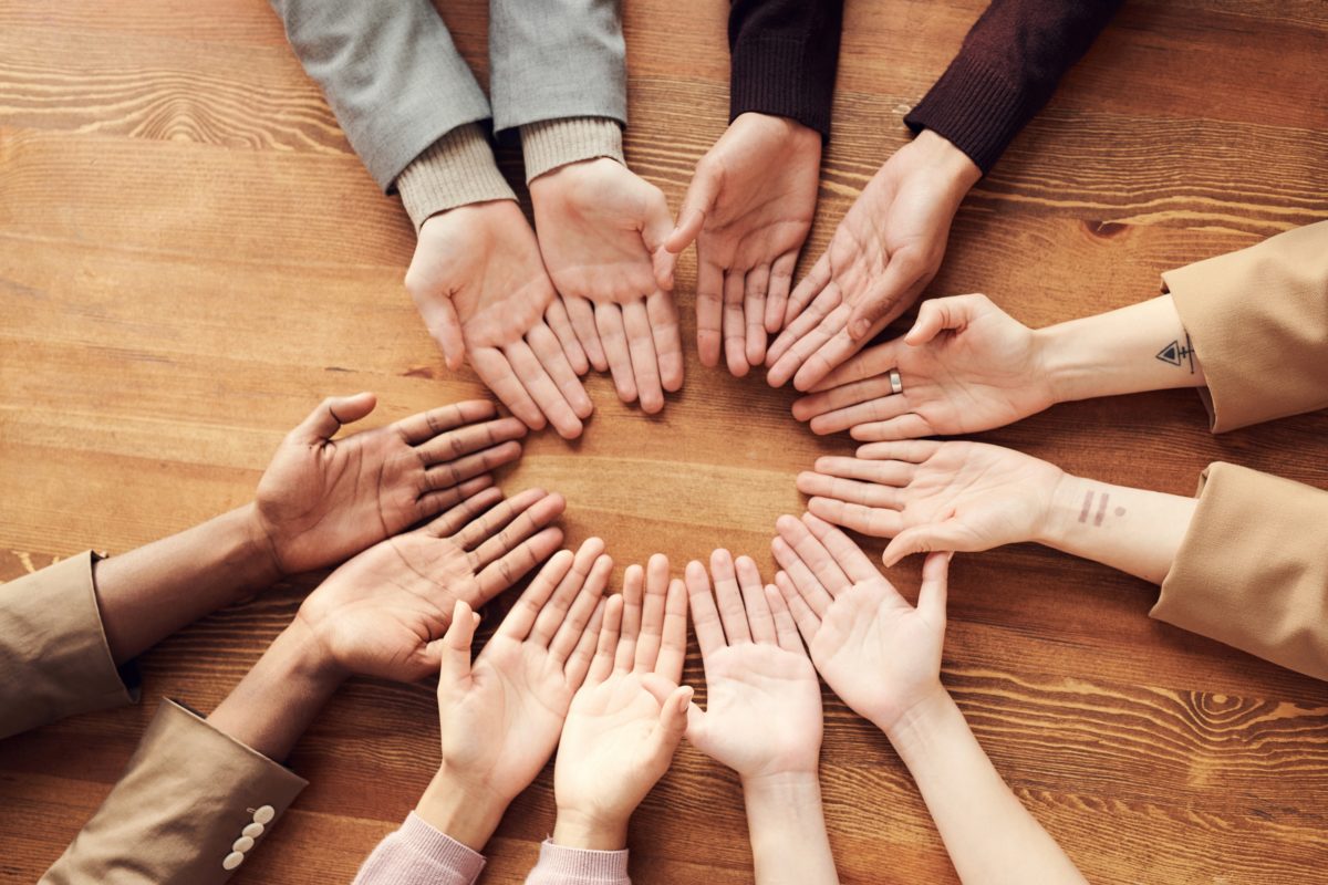 Hands in a circle of different ethnicities demonstrating inclusion.